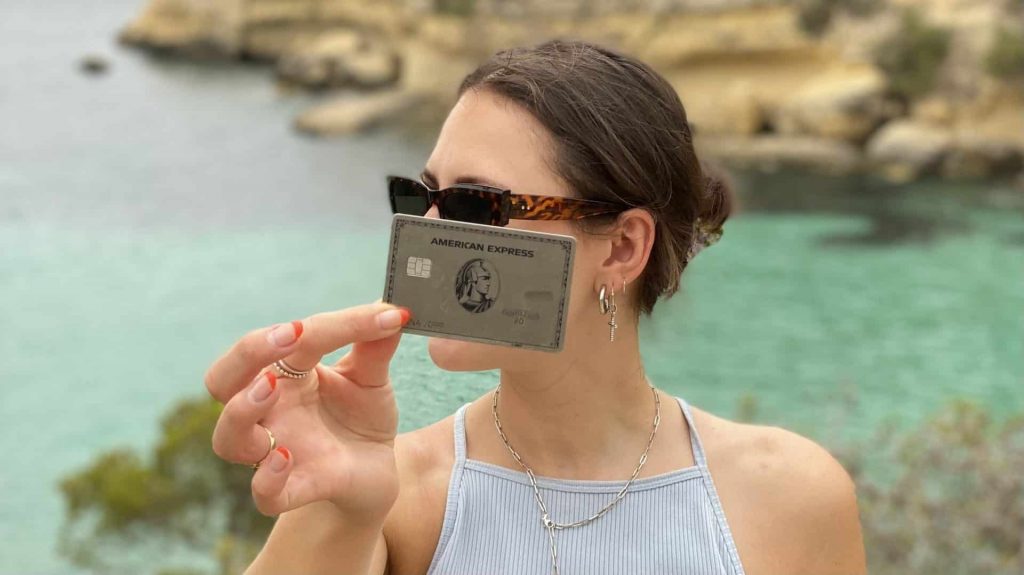 Femme tenant une Amex Platinum, mer en arrière-plan